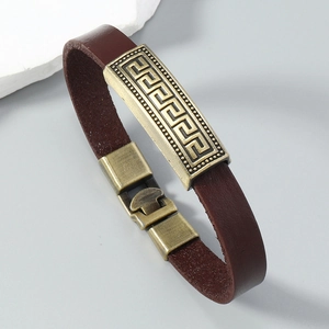 Detail of vintage brown leather bracelet with engraved brass plates and Greek key pattern