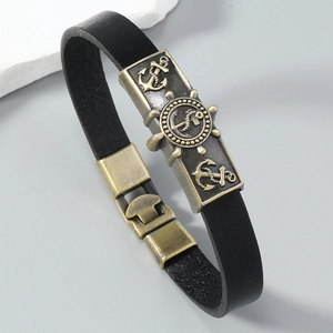 Close-up of vintage leather nautical bracelet with bronze rudder and anchor emblems