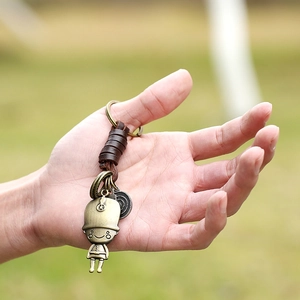 Vintage bronze cartoon figure keychain with woven leather wrap held in hand
