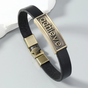 Dettaglio del bracciale in pelle nera vintage con incisione in bronzo e chiusura in metallo