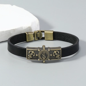 Detail of nautical leather bracelet with bronze helm and anchor charms on gray background