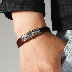 Vintage brown leather nautical bracelet featuring bronze anchor and helm plaque detail