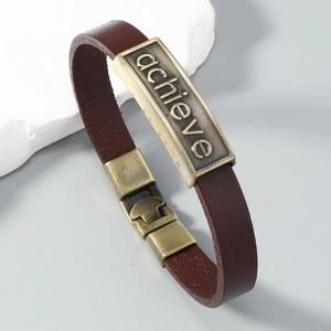 Dettaglio del bracciale in pelle marrone scuro con piastra in bronzo inciso e fibbia metallica