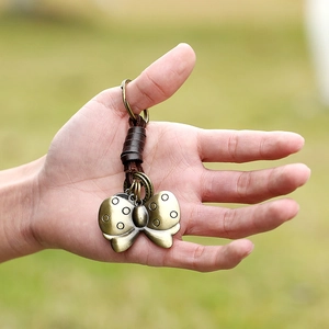 Vintage bronze butterfly pendant keychain with dark brown leather wrap on hand