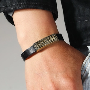 Detail of the vintage black leather bracelet featuring a bronze Greca pattern alloy plate