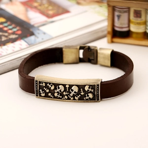 Gros plan d'un bracelet en cuir vintage avec reliefs de crânes en bronze et fermoir métal