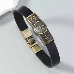 Macro detail of black leather bracelet with bronze Tai Chi Yin Yang symbol and alloy buckle