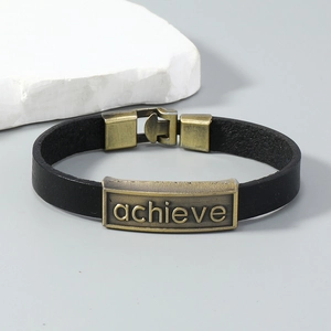 Dettaglio del bracciale in pelle nera con placca in bronzo e incisione achieve