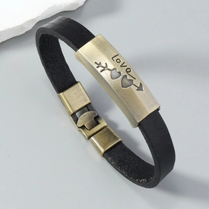 Macro shot of black leather strap with vintage brass Cupid's arrow and Love engraving