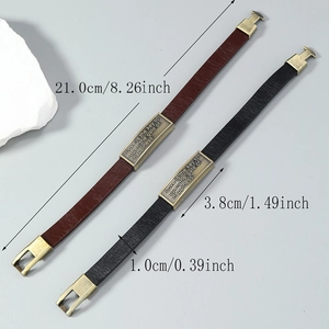 Vintage leather bracelets for men with engraved bronze plate on grey stone background