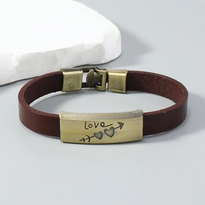 Detailed macro shot of vintage brown leather bracelet with Love engraved bronze plaque