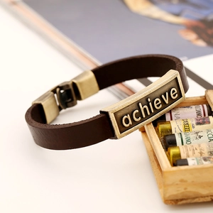 Close-up of vintage brown leather bracelet featuring engraved achieve metal plaque