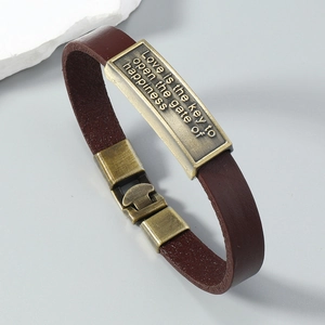 Detail of vintage brown leather bracelet with engraved bronze plate and metal clasp