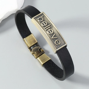 Macro detail of retro leather bracelet with bronze 'believe' engraved metal plate