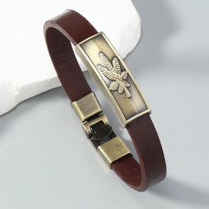 Detailed macro of vintage brown leather bracelet with bronze maple leaf metal plate