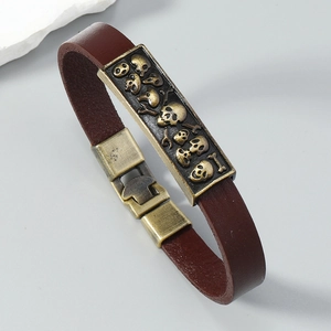 Close-up of retro leather bracelet with bronze skull charms and mushroom snap buckle