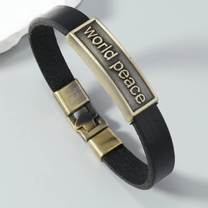 Close-up of black leather bracelet featuring an engraved bronze World Peace metal plate