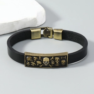 Macro detail of punk leather bracelet with bronze skull relief and buckle closure