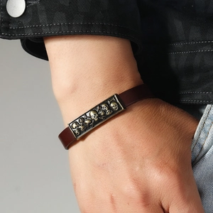 Retro punk brown leather bracelet featuring embossed bronze skull charms on metal plate
