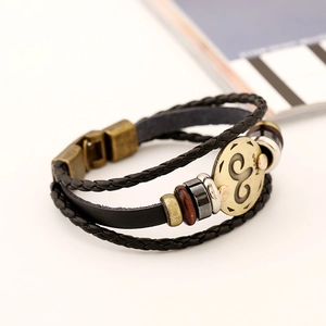 Close-up of Aries zodiac leather bracelet with bronze metal charm and braided cord