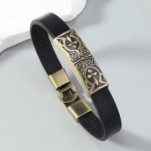 Detail of a punk leather bracelet with a bronze relief cross plate and stitch texture