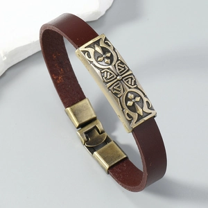 Detail of vintage leather bracelet featuring bronze cross relief and textured metal plate
