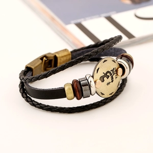 Macro shot of Virgo leather bracelet featuring vintage gold emblem and braided black ropes