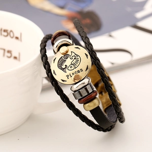 Macro detail of braided leather Pisces bracelet with antique bronze zodiac charm and beads