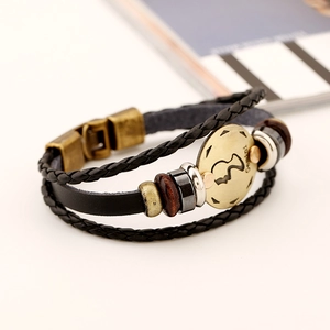 Macro detail of multilayer Gemini zodiac leather bracelet with bronze charms and wooden beads