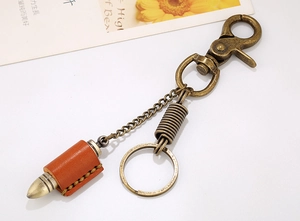 Close-up of vintage leather keychain with bullet pendant and rustic brass clasp