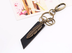 Macro shot of vintage bronze feather pendant and black leather strap on keychain