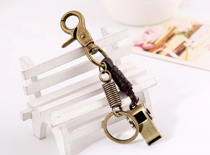 Close-up of vintage brass keychain with leather wrap and whistle on a decorative prop