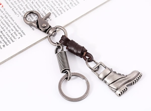 Close-up of vintage leather keychain with silver alloy boot pendant on a book
