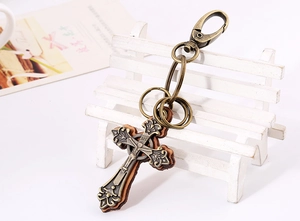 Vue détaillée du porte-clés croix vintage en bronze avec cuir brun sur un petit banc
