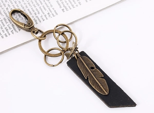 Detail of vintage bronze feather charm with leather base on a horseshoe keychain hook