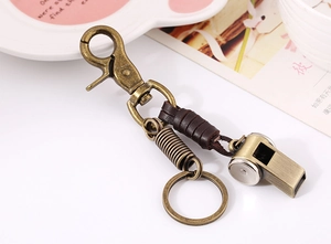 Macro view of vintage bronze alloy whistle and brown leather weaving on keychain