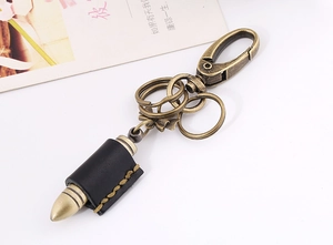 Detail view of retro bullet-shaped keychain with black leather wrap and brass hardware