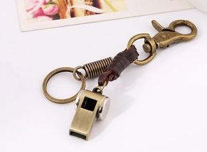 Detail of vintage bronze whistle keychain with dark brown woven leather strap
