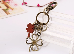 Detail of vintage clover keychain with bronze metal and reddish-brown leather leaf