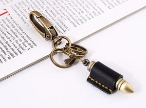 Detail of vintage cowhide keychain with brass bullet pendant and handcrafted stitching