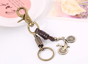Close-up of vintage bronze bicycle charm and leather strap on metal keychain