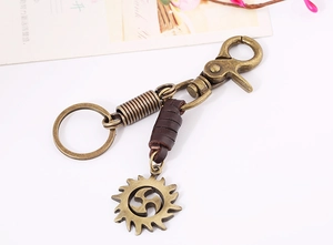 Macro shot of vintage leather keychain with bronze sun pendant and lobster clasp detail