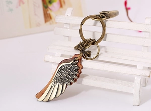 Detail of vintage bronze wing keychain with brown leather on a decorative wooden bench