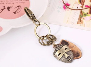 Detailed view of vintage bronze African mask charm on genuine leather keychain
