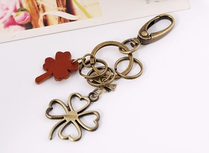Detailed macro view of vintage bronze four-leaf clover keychain with brown leather charm