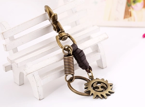 Close-up of vintage bronze alloy keychain with leather strap and gear pendant detail