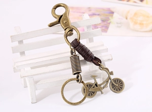 Detail of vintage bronze bicycle keychain with brown leather wrap on a mini bench