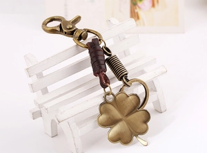 Macro detail of retro bronze four-leaf clover keychain with dark brown leather strap