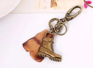 Macro detail of retro bronze shoe pendant and brown leather on vintage keychain