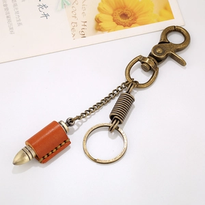Retro bronze bullet keychain with orange cowhide leather cover on white background